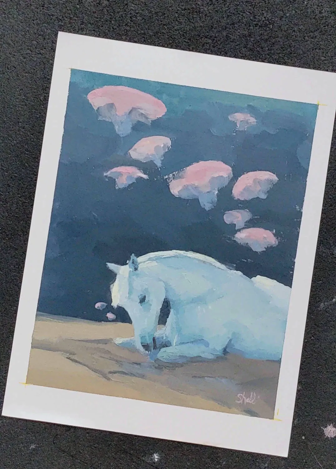 pale blue-white horse lying on tan sandy ground with head lowered, against a deep teal-blue field; six or seven pink jellyfish-like shapes drift in the upper portion of the painting; white paper margin visible around the edges