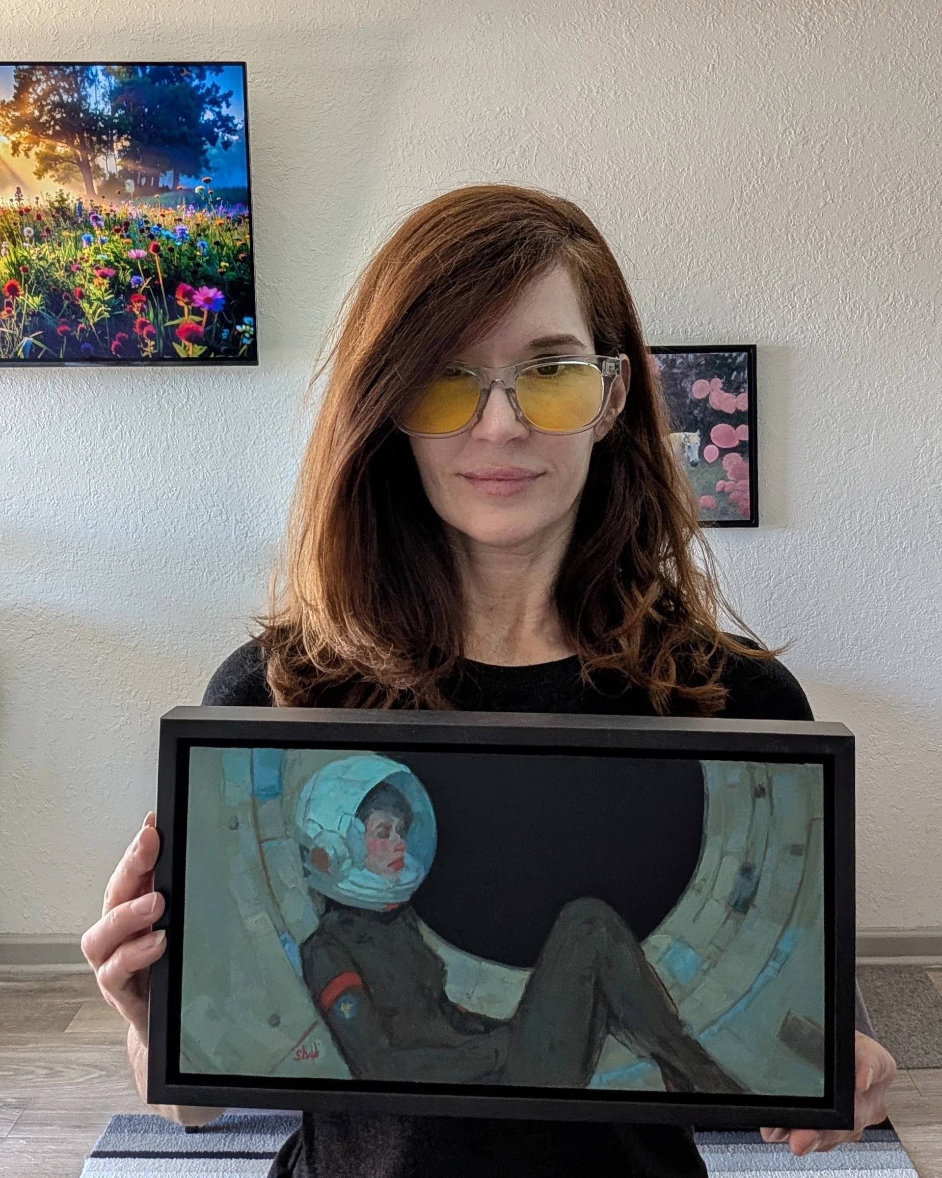 the artist holding the framed painting She Floats in the Quiet