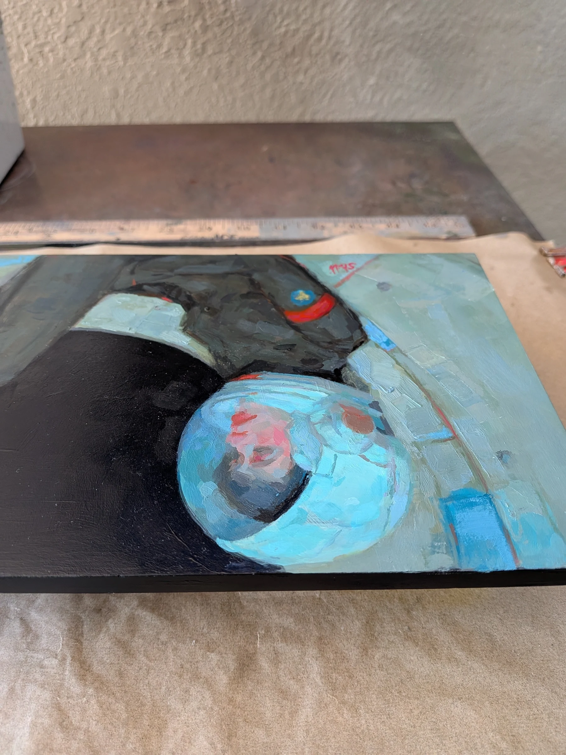edge view of the painting She Floats in the Quiet lying on a table