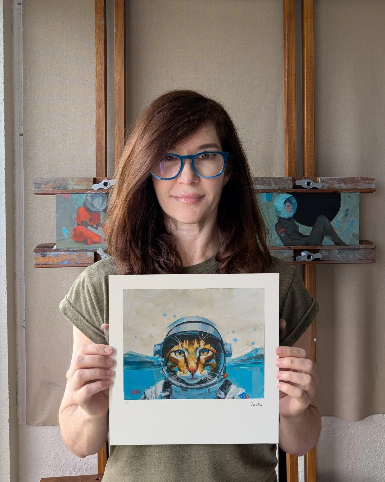 artist holding a small limited-edition print of Cat Astronaut