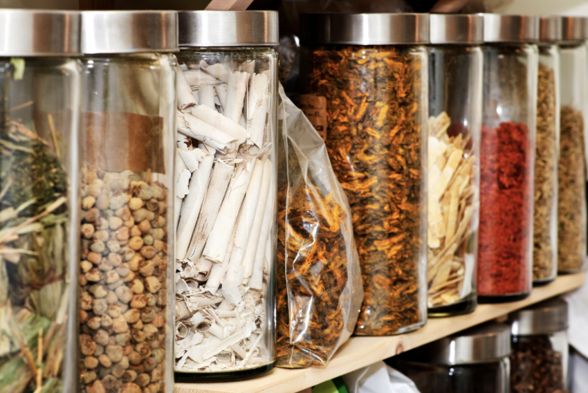 Jars of Chinese herbs lined up on a shelf.