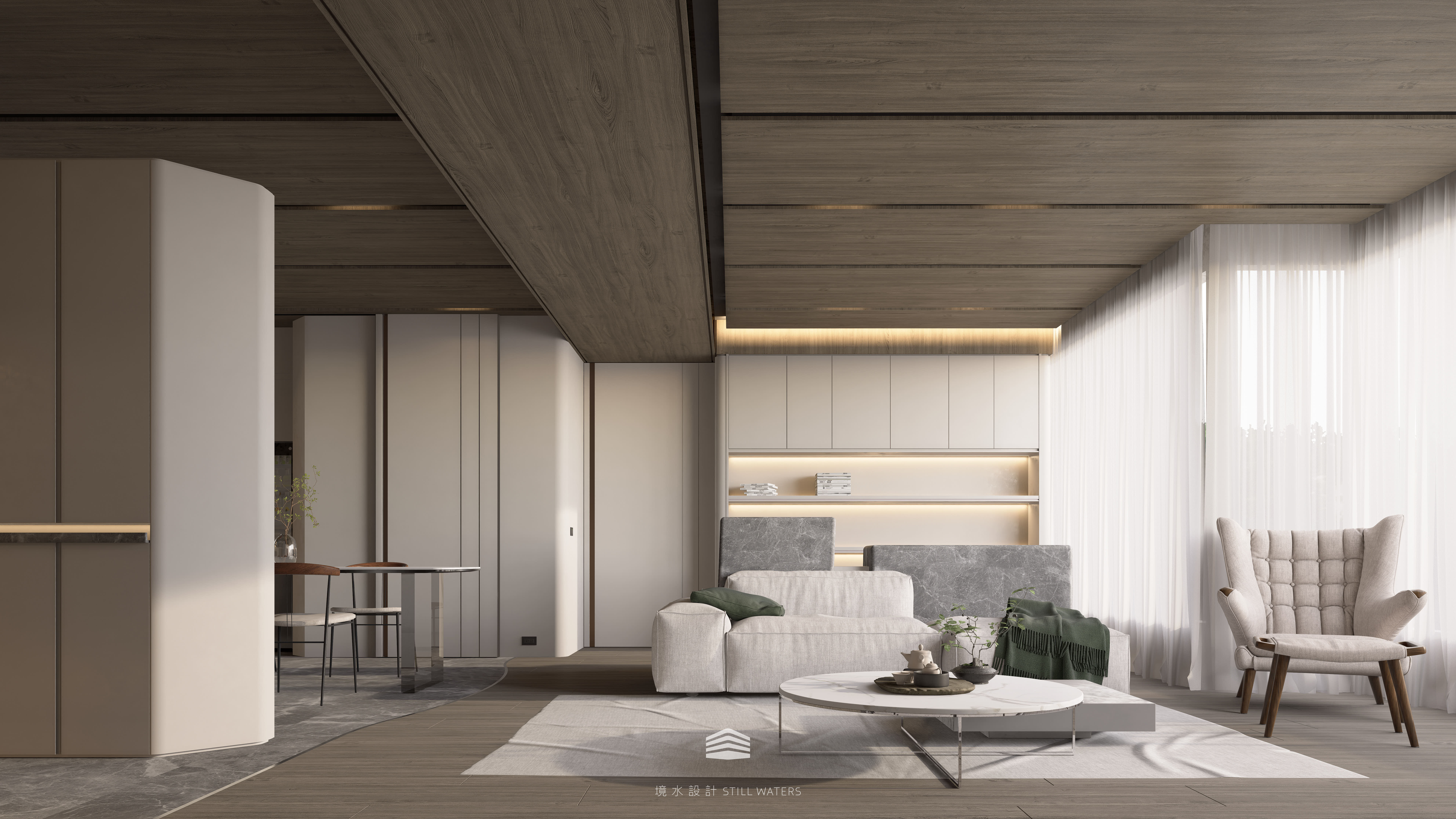 《靜映歲月》客廳以灰石立面與布質沙發交織層次，隱藏門延展牆面線條，壁面轉角以圓弧收邊取代銳角，兼具安全與柔和。柔光漫映之間，生活與靜謐共生。 The “Silent Years” living area blends stone textures and fabric seating, with curved wall edges replacing sharp corners for safety and softness, allowing tranquility and everyday life t