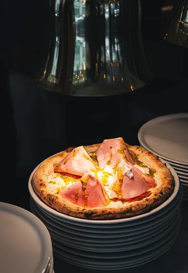 Pizza italienne fraîchement cuite servie sur des assiettes empilées au restaurant Tivoli