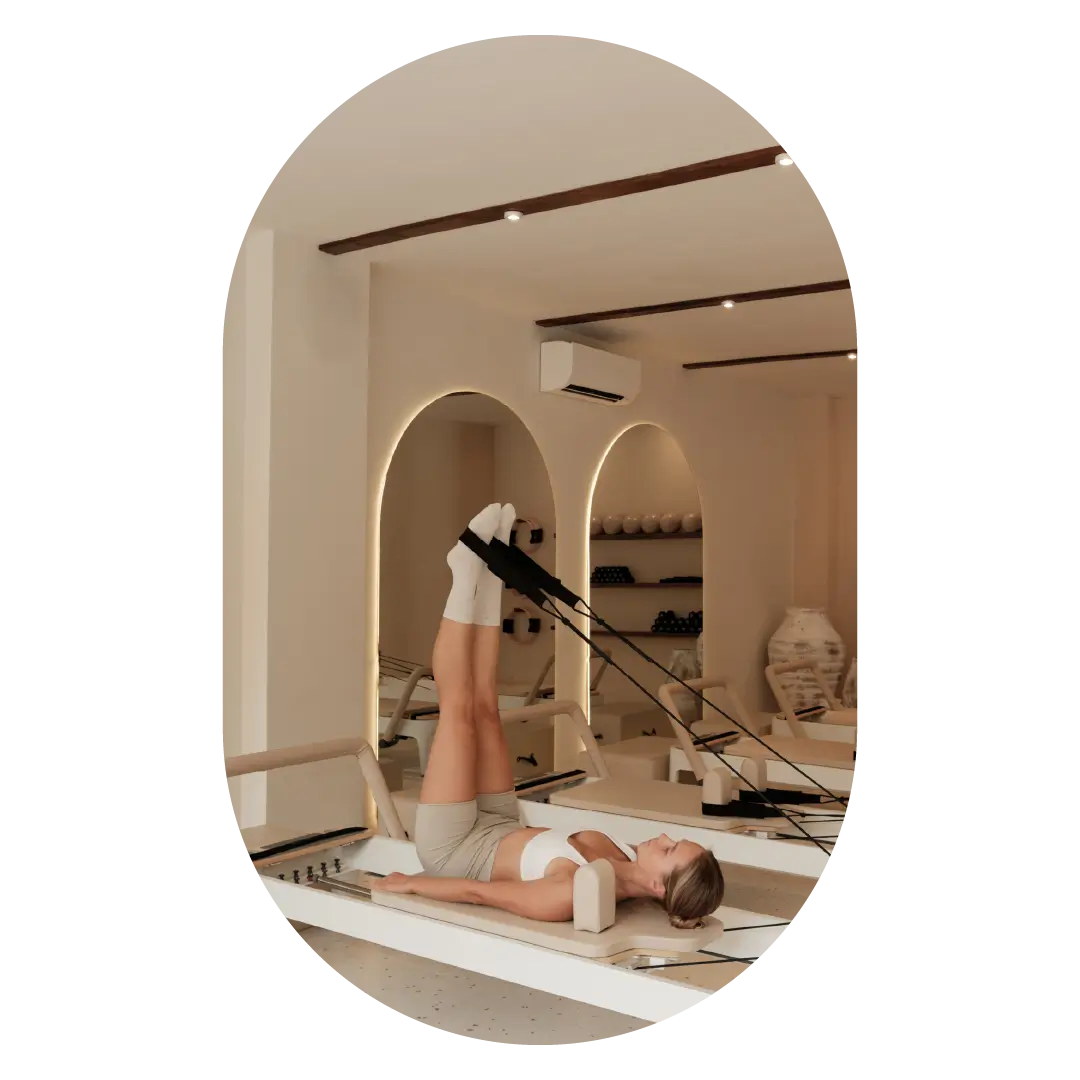 Nő reformer pilates gyakorlatot végez a TMS Reformation studioban egy reformer gépen.