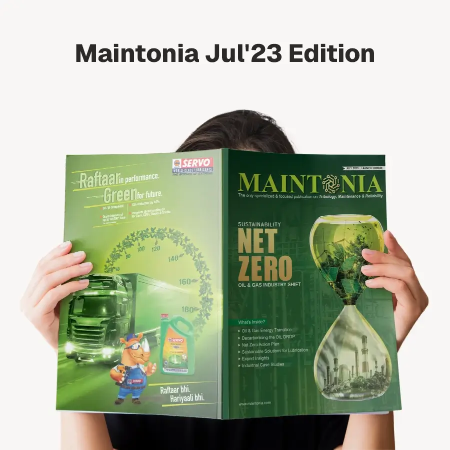 Person holding the July 2023 edition of Maintonia magazine featuring sustainability and net zero in oil and gas industry with a green-themed cover showing an hourglass with industrial imagery and a truck advertisement.