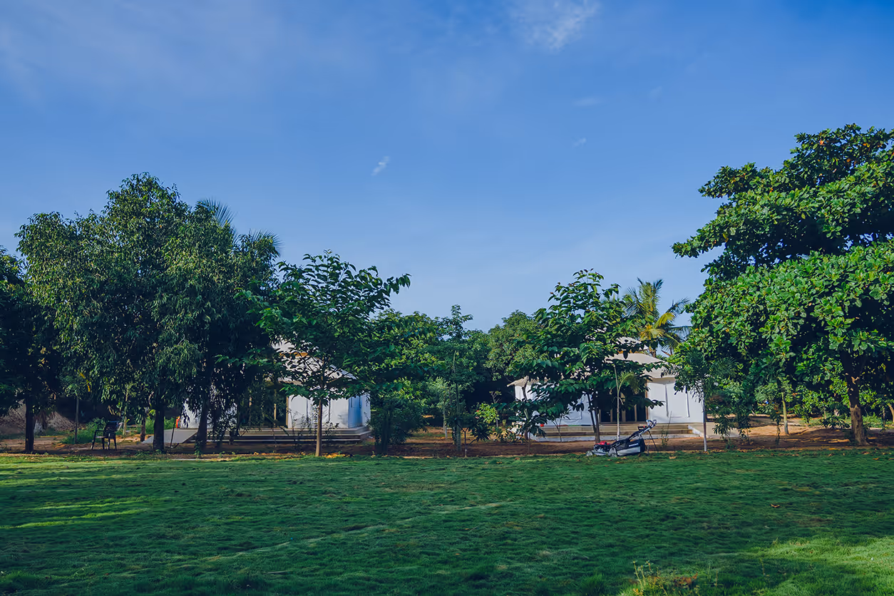 A wide view of the lush green lawns and glamping tents at Angirasa resort, showcasing the spacious and serene environment for a nature getaway near Hyderabad.