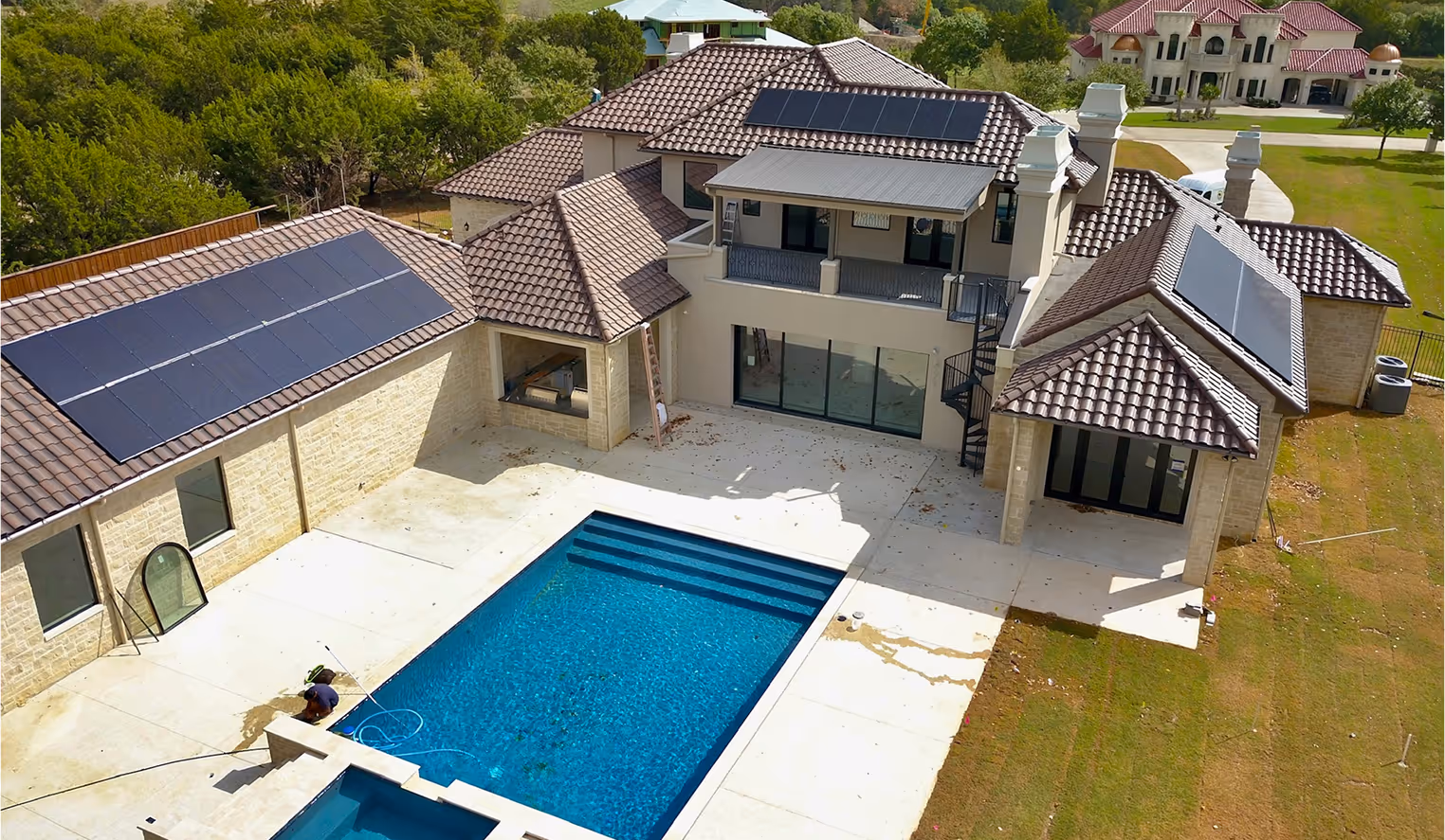 Modern house with multiple solar panels on the roof and a blue swimming pool in the backyard.