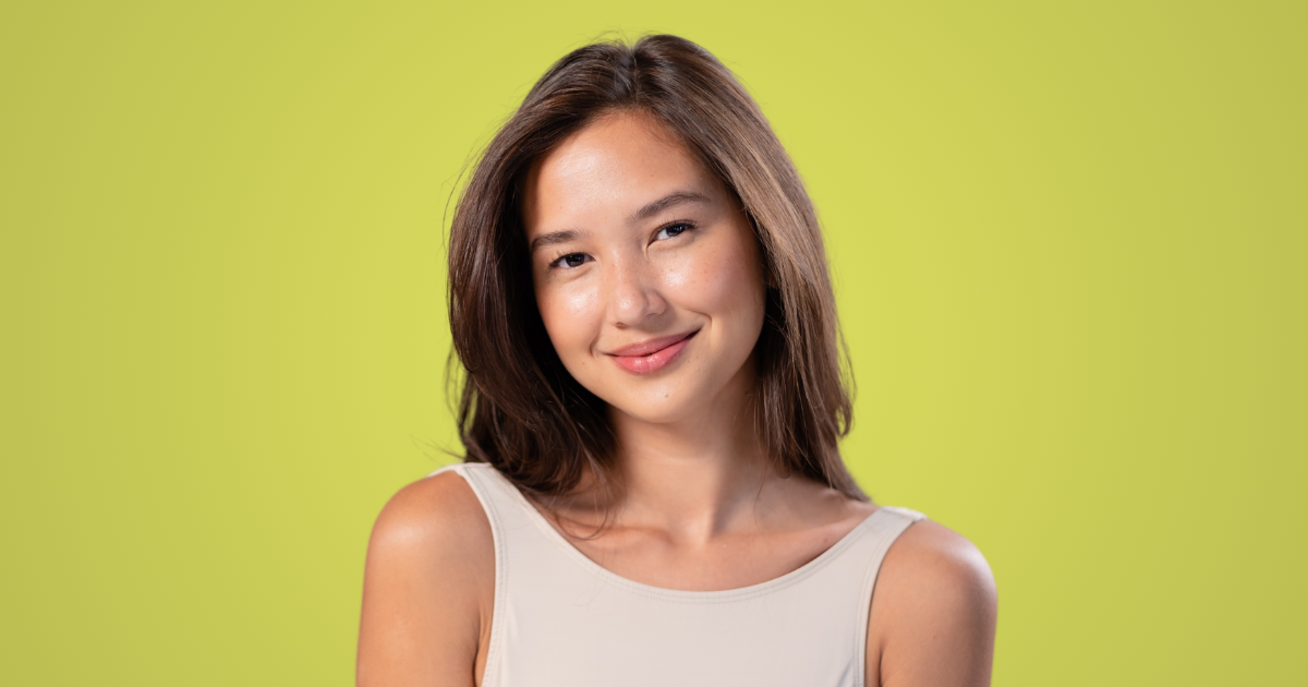 Une femme souriante en haut blanc pose pour la photo.