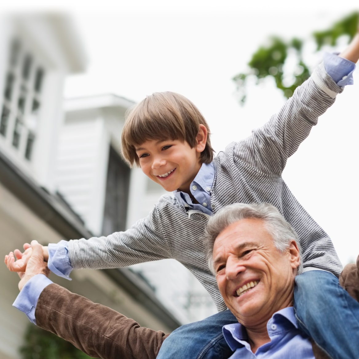 Grandfather carrying his smiling grandson on shoulders