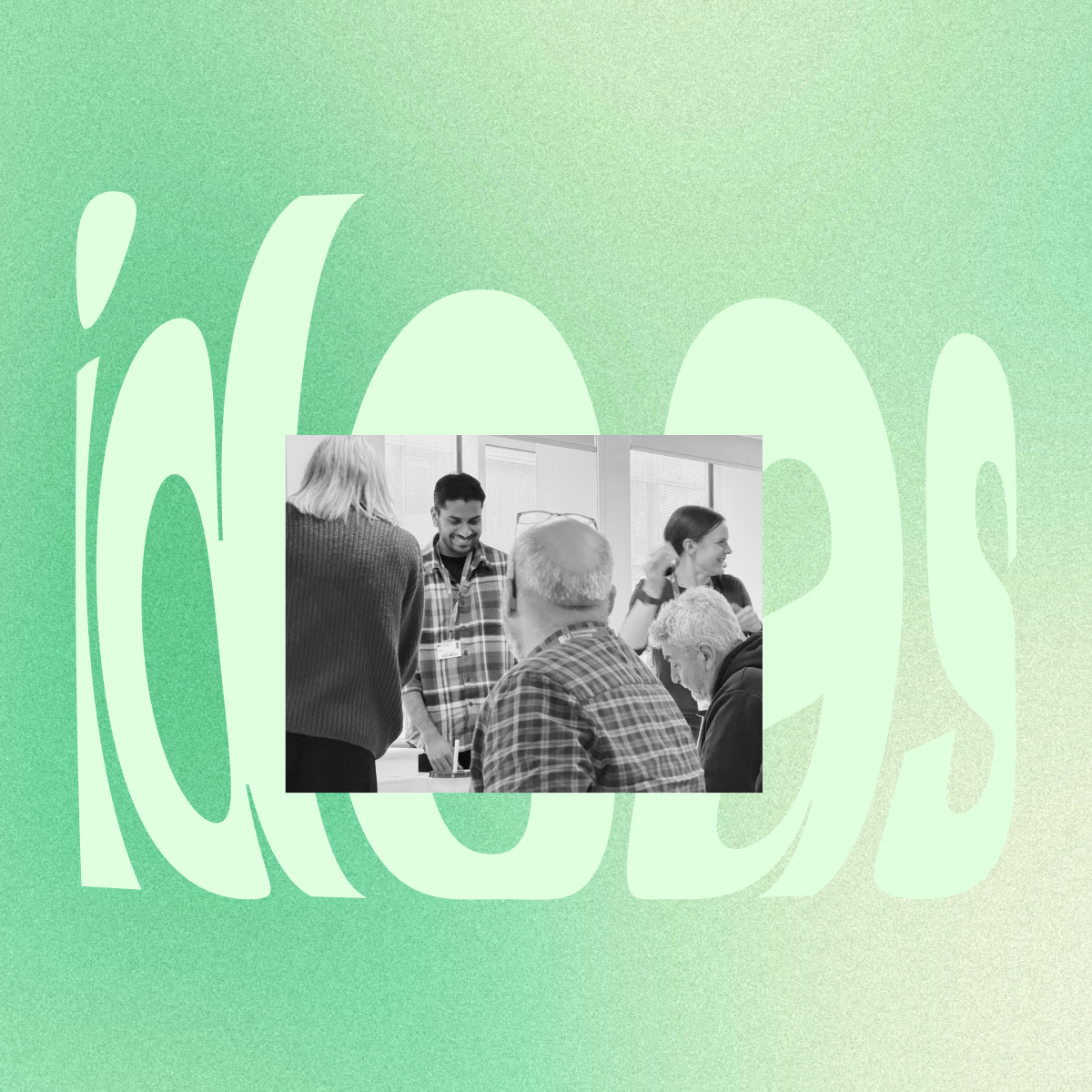 Group of five people engaged in conversation and working together around a table in a bright room with large windows.