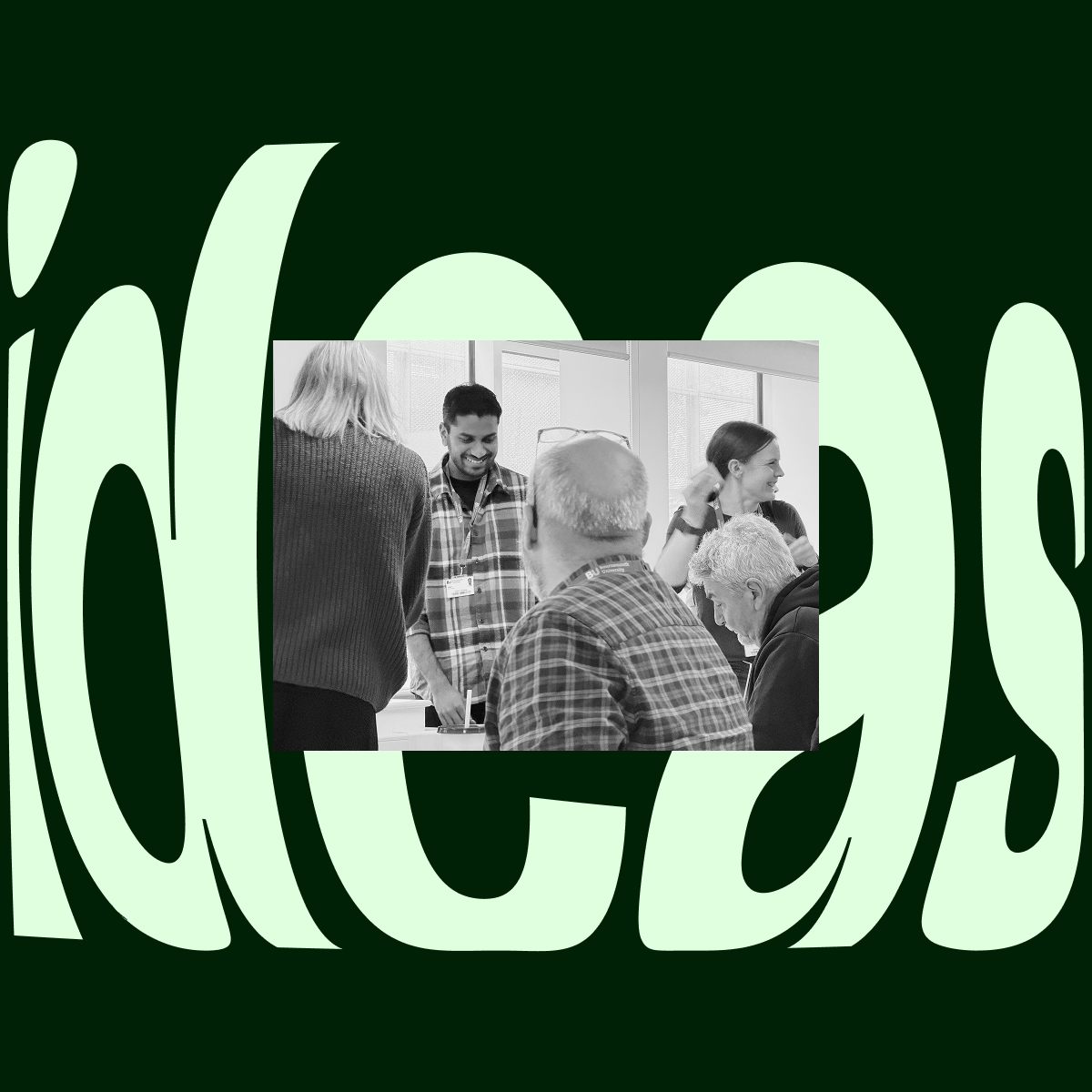 Group of five people engaged in conversation and working together around a table in a bright room with large windows.