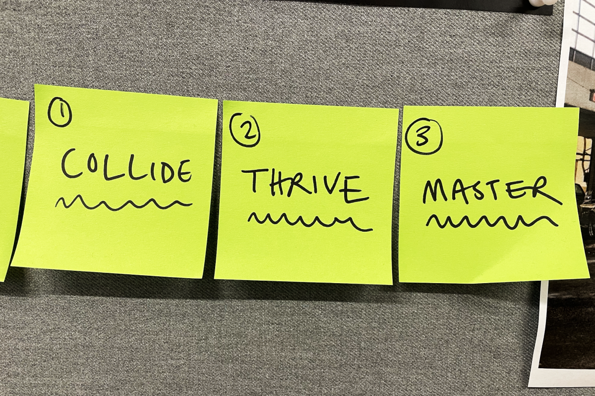 Three yellow sticky notes on a gray fabric surface labeled 1 to 3 with the words 'COLLIDE', 'THRIVE', and 'MASTER' each underlined with a wavy line.