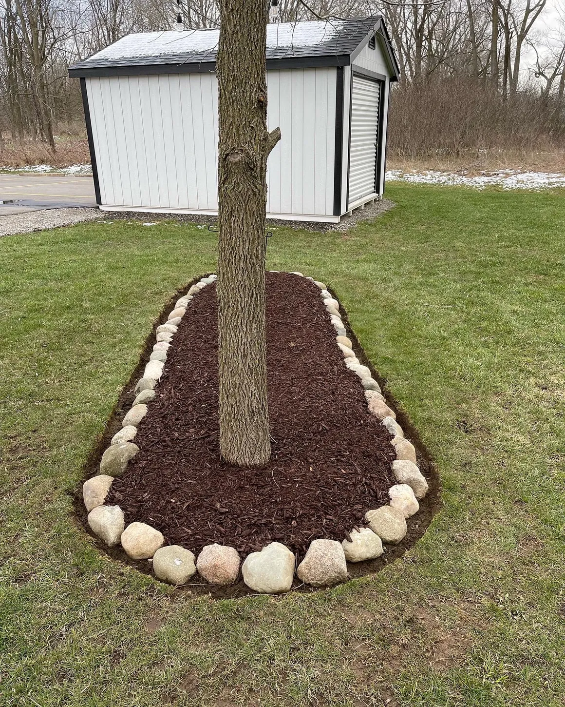 Tree mulching and landscaping service with decorative stone border by Jake's Lawn Care Michigan