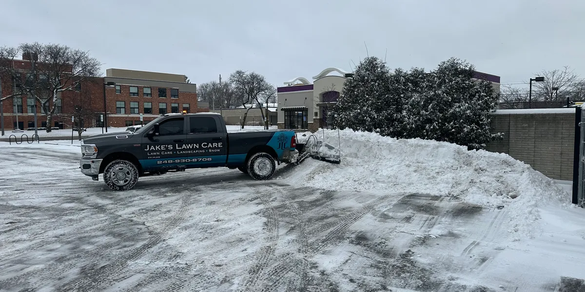 Jake's Lawn Care branded snow plow truck providing winter maintenance services in Michigan