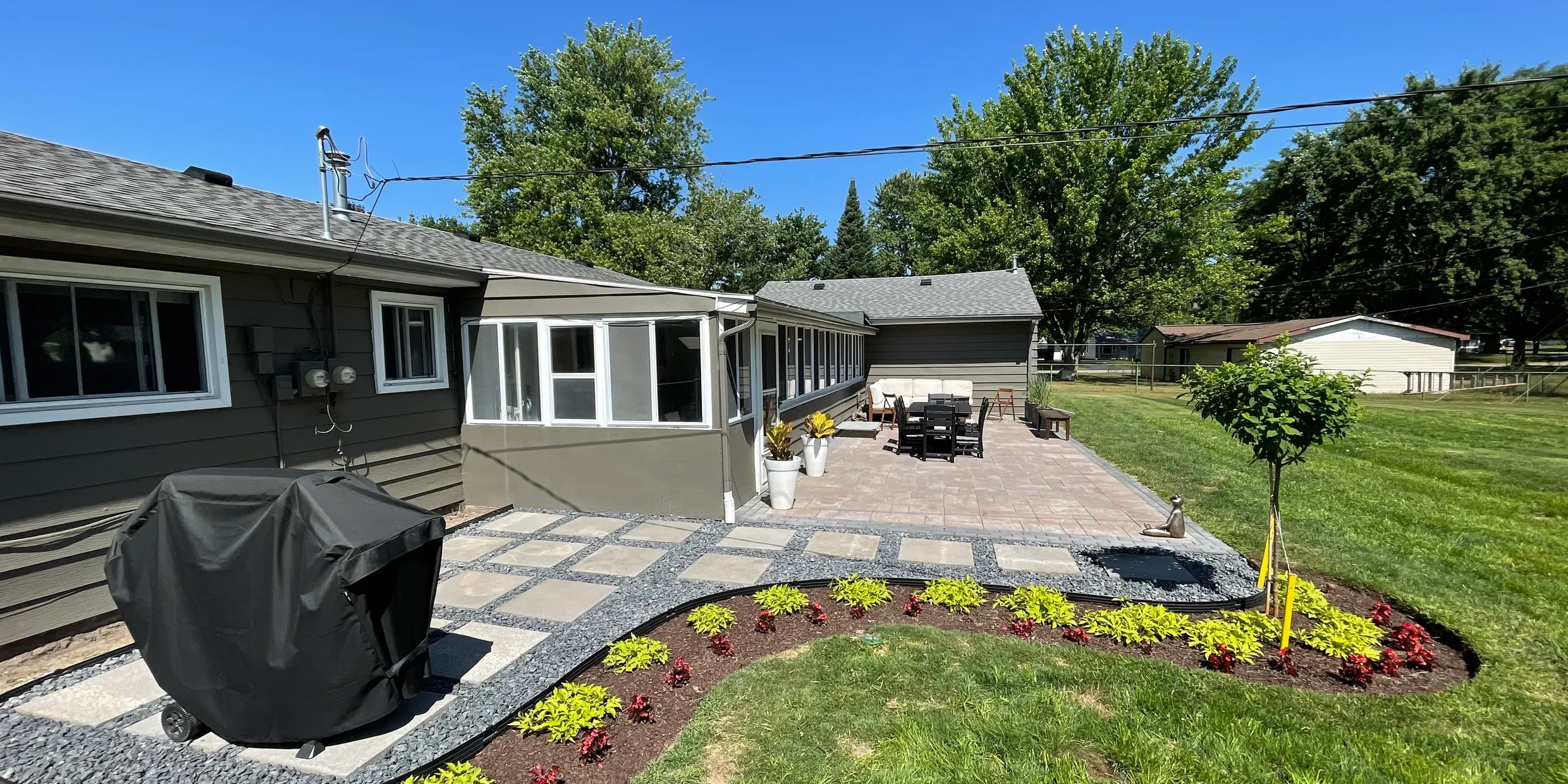 Custom patio installation and landscape design by Jake's Lawn Care with decorative plantings Michigan
