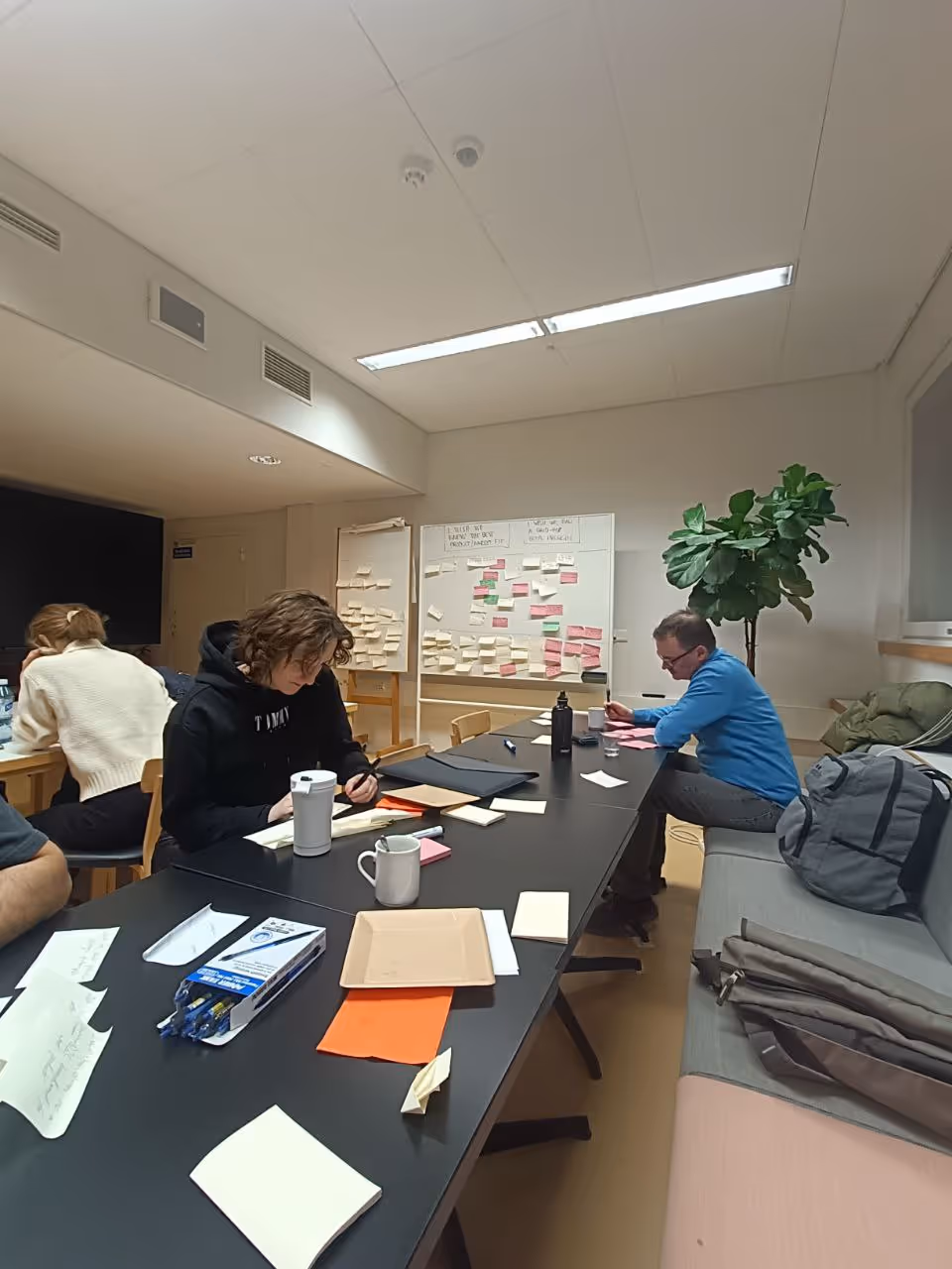 A full view of the whiteboards and everybody on the team working with the CEO to map out the core brief questions