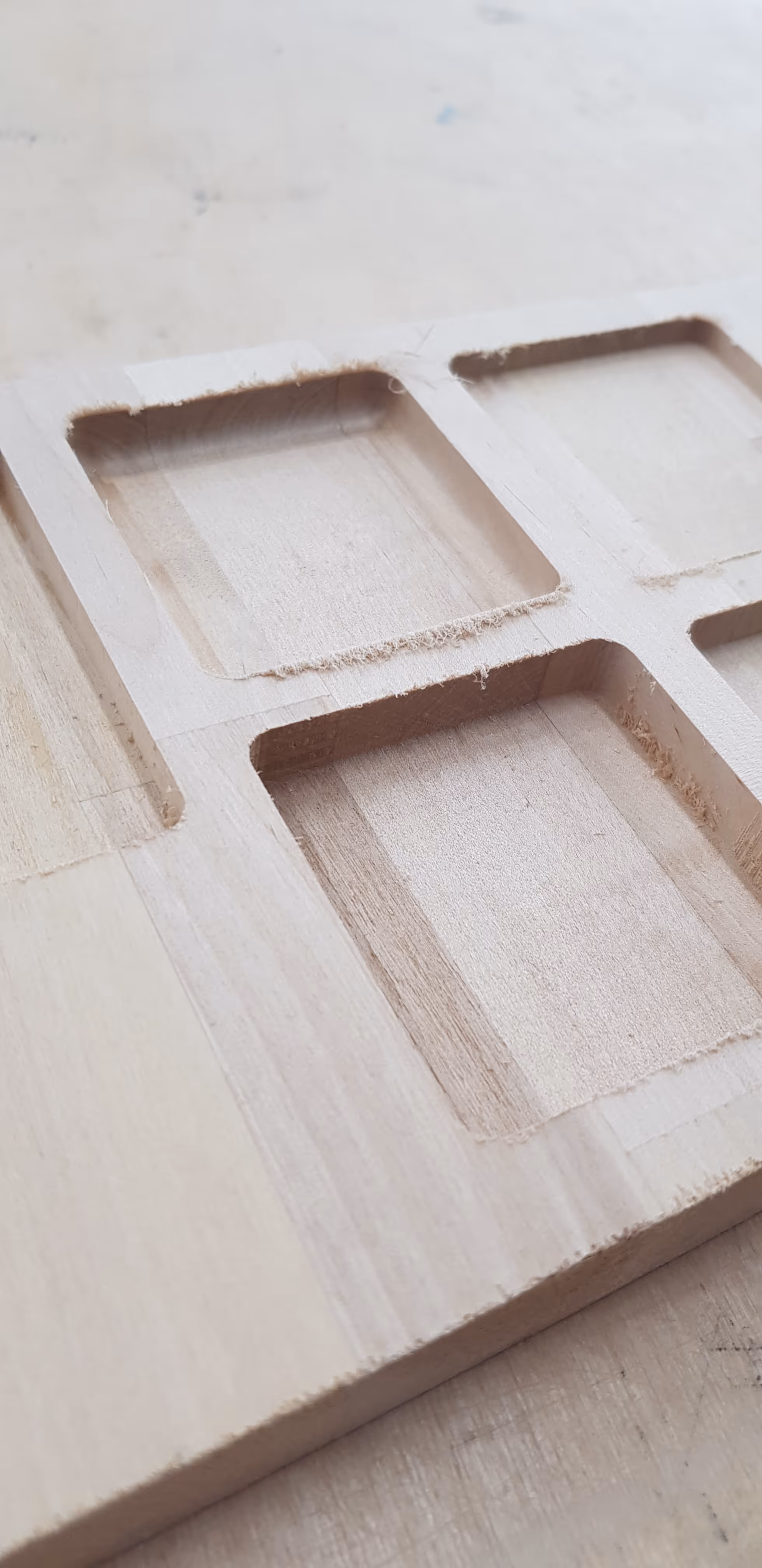 A photo of a wooden board with CNC'd holes in it to test the box sizes.