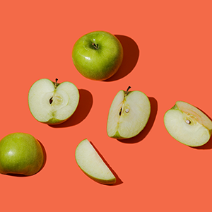 green apples and apple slices on an orange background