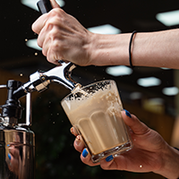 hands getting cold brew coffee from a tap
