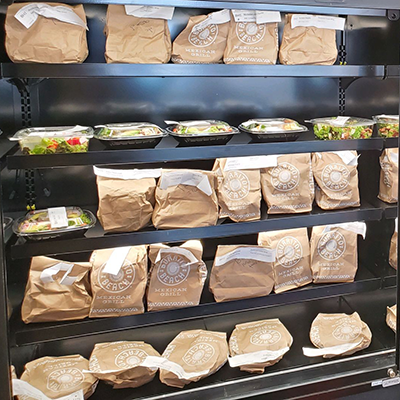 Shelves of packaged lunches with labels on them, waiting to be picked up.