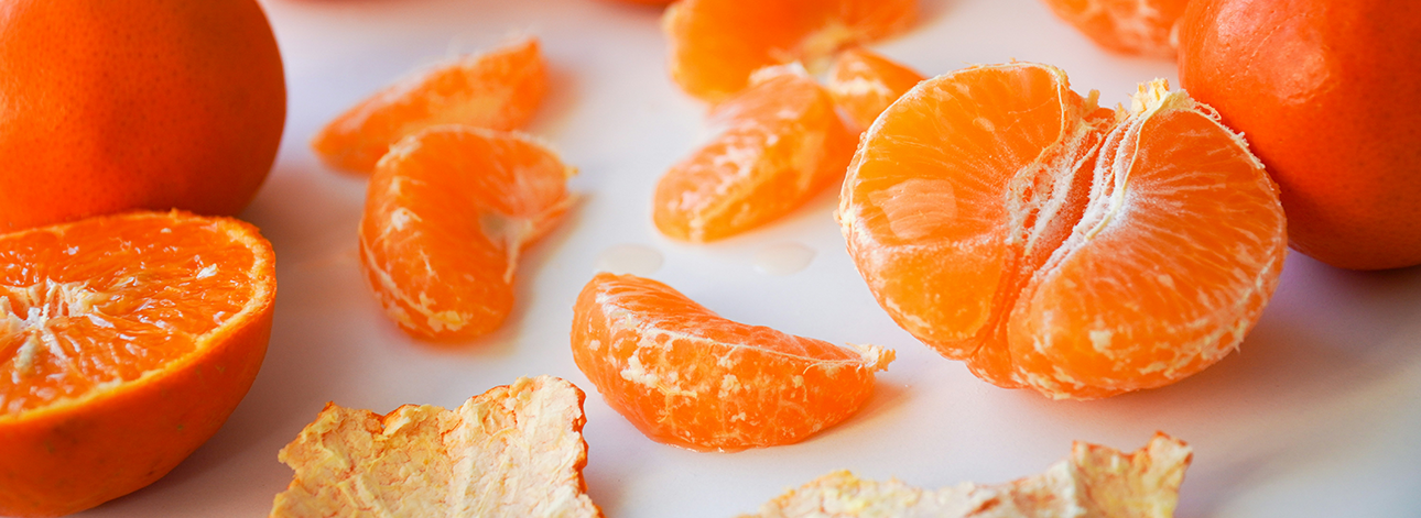 several clementine oranges, one cut in half, one peeled and segmented.