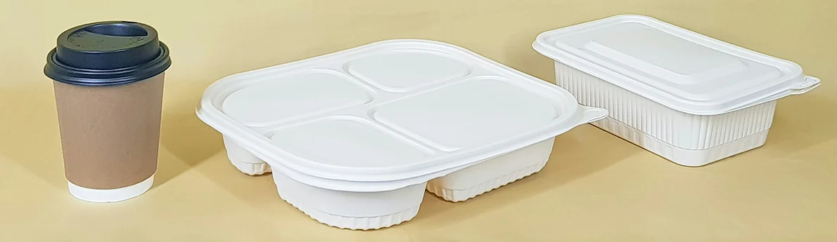 sustainable food packaging on a yellow background, including a coffee cup, a multi-compartment container, and a single compartment container.