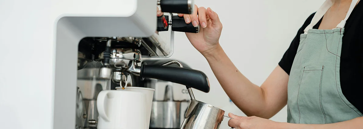 Barista steams milk on a large espresso machine.