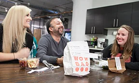 team members at BenchPrep laughing while eating together at a wooden table