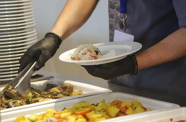 Buffet style service - Canteen worker at serving line putting food on the plate