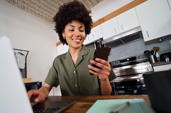 photo of happy smiling woman holding smartphone using cellphone and laptop technology