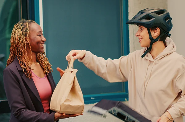 photo of fastfood courier delivering takeaway meal in paperbag