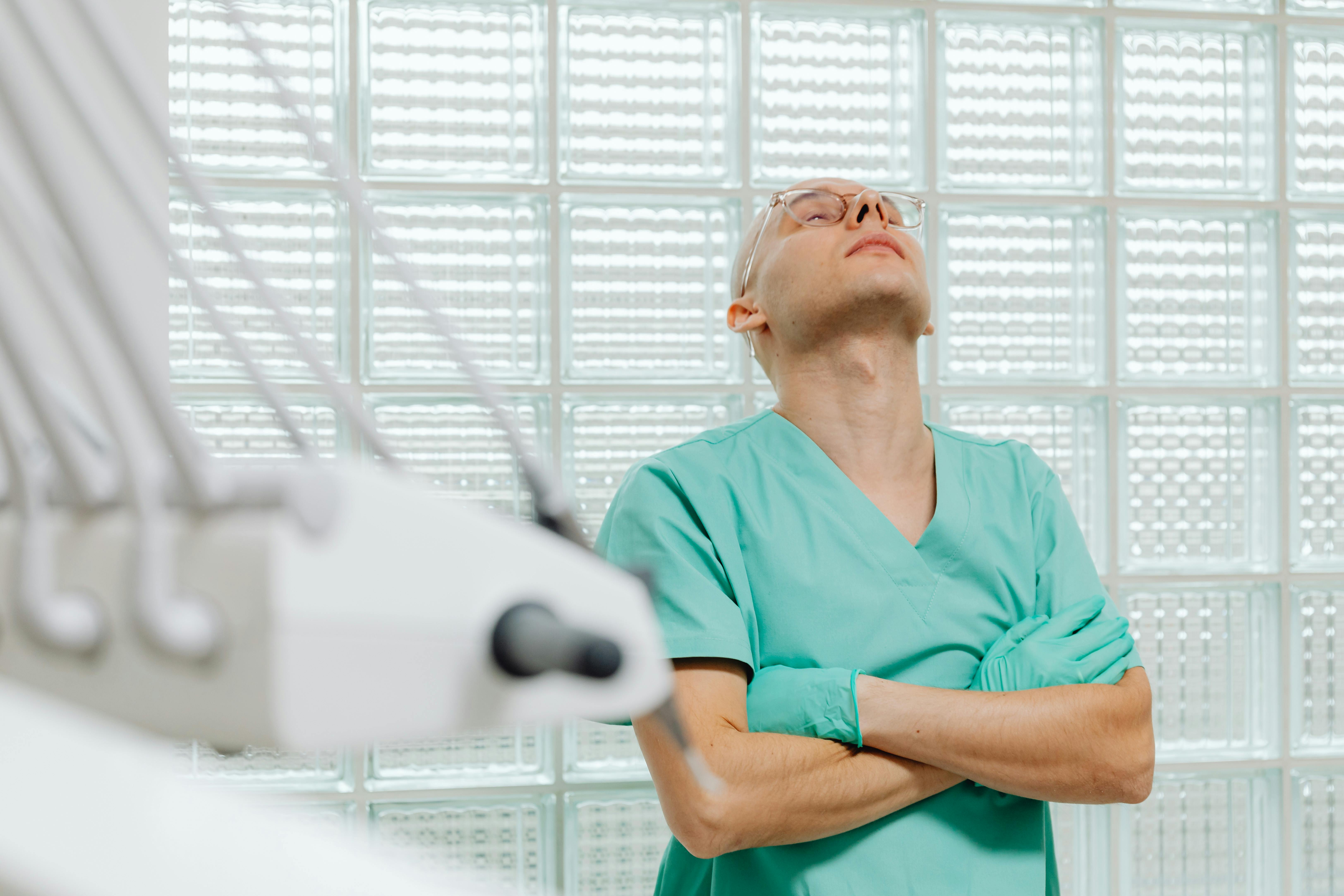 Tired nurse rests his head back against wall