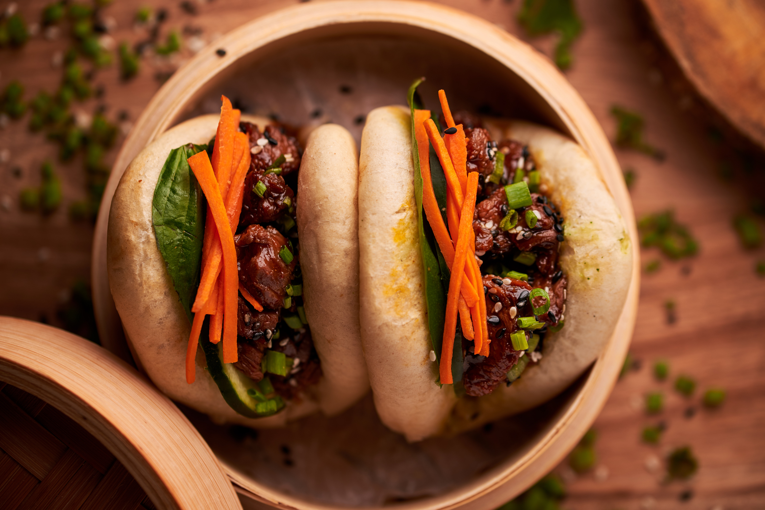 Two buns filled with meat and veggies in a steamer