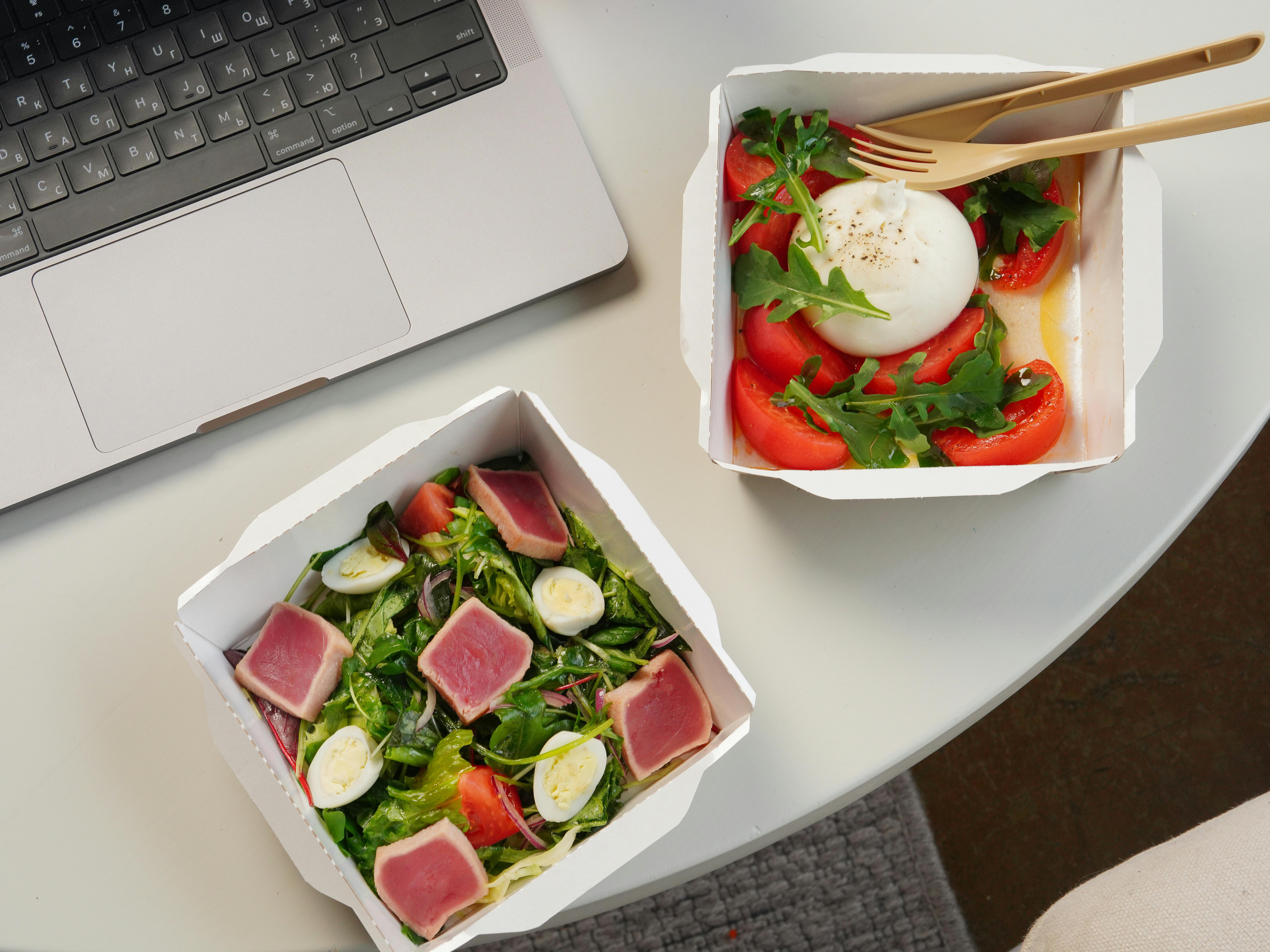 Two take-out salad containers on a desk