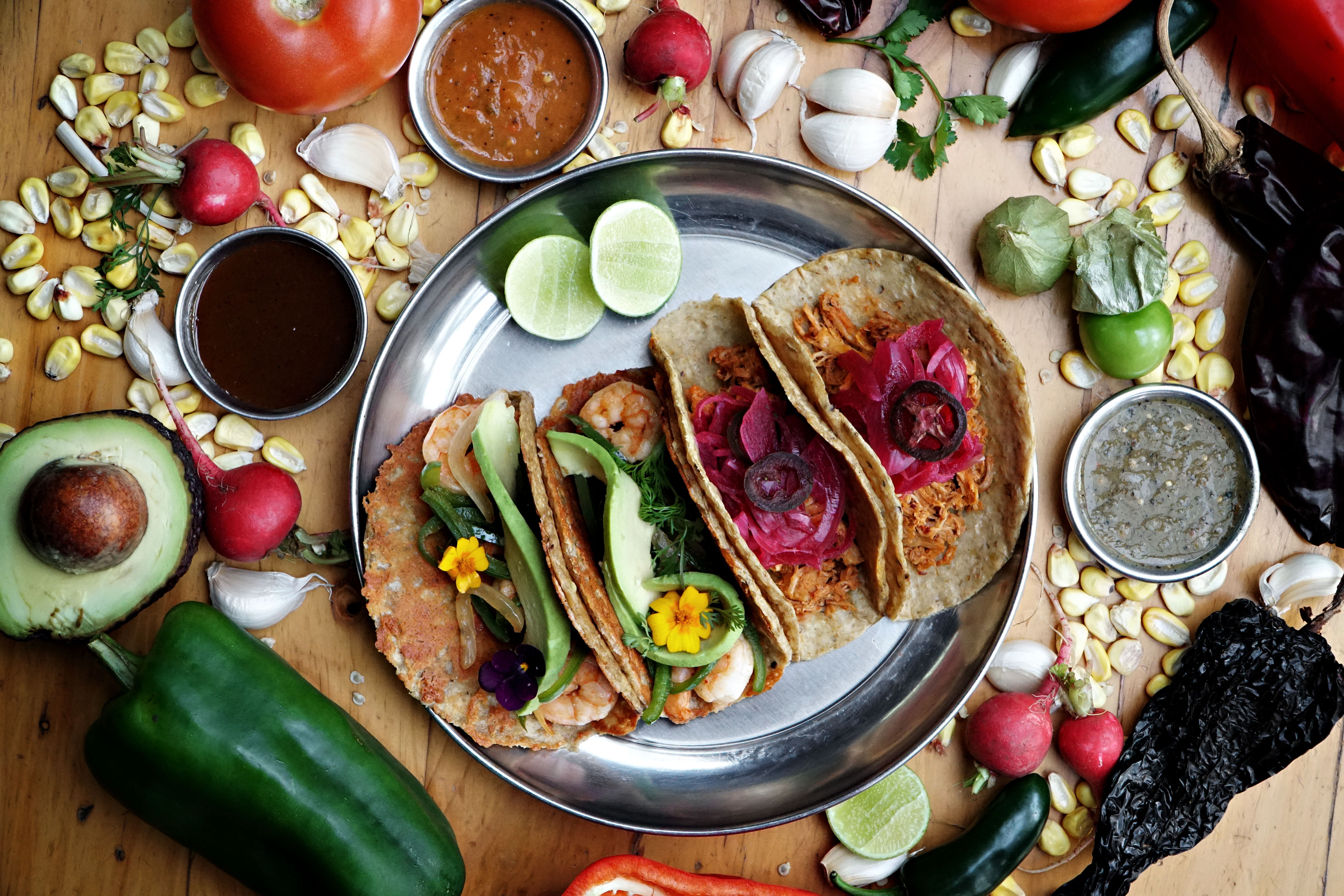 Tacos on a plate with ingredients surrounding them