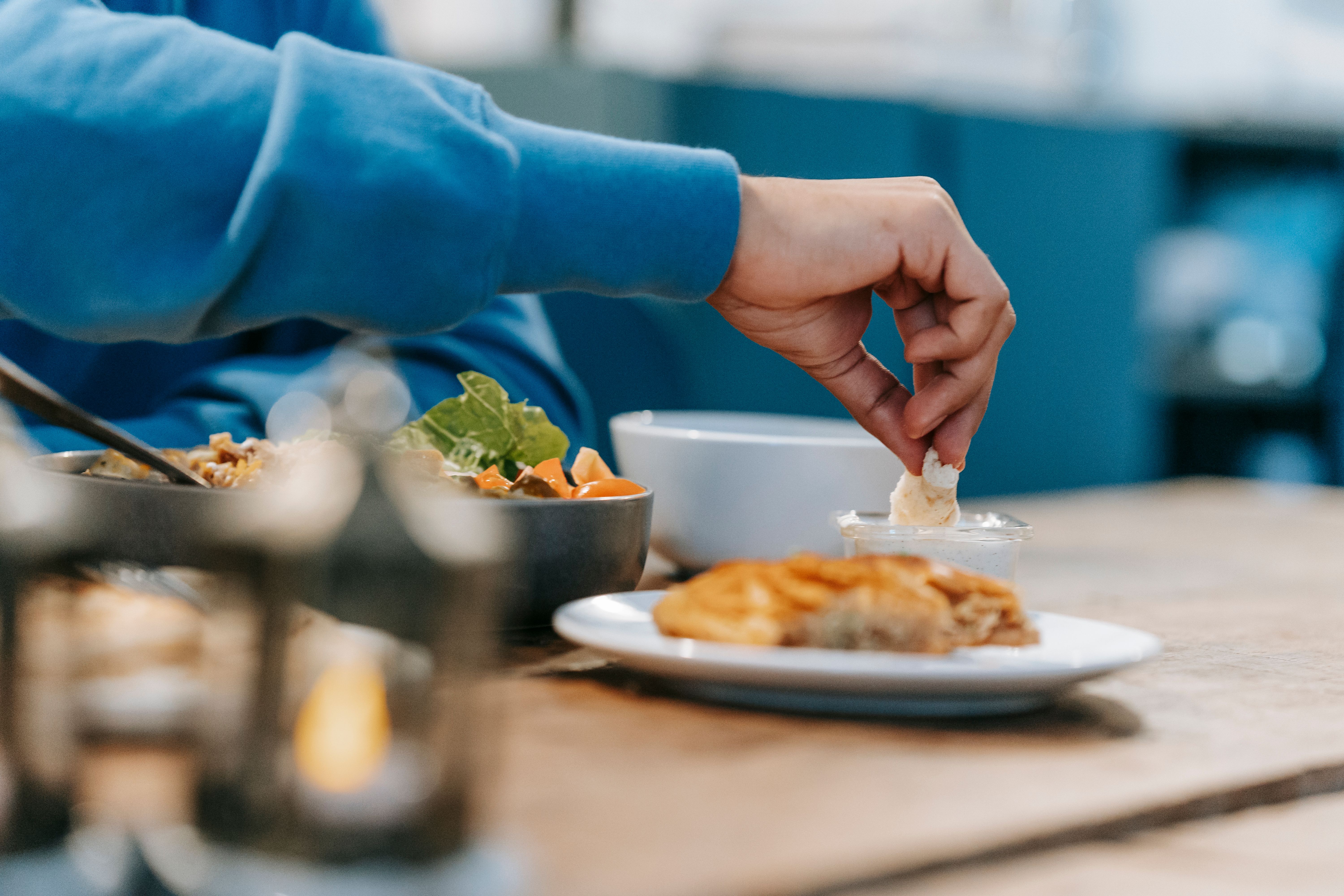 Person dipping food into a sauce