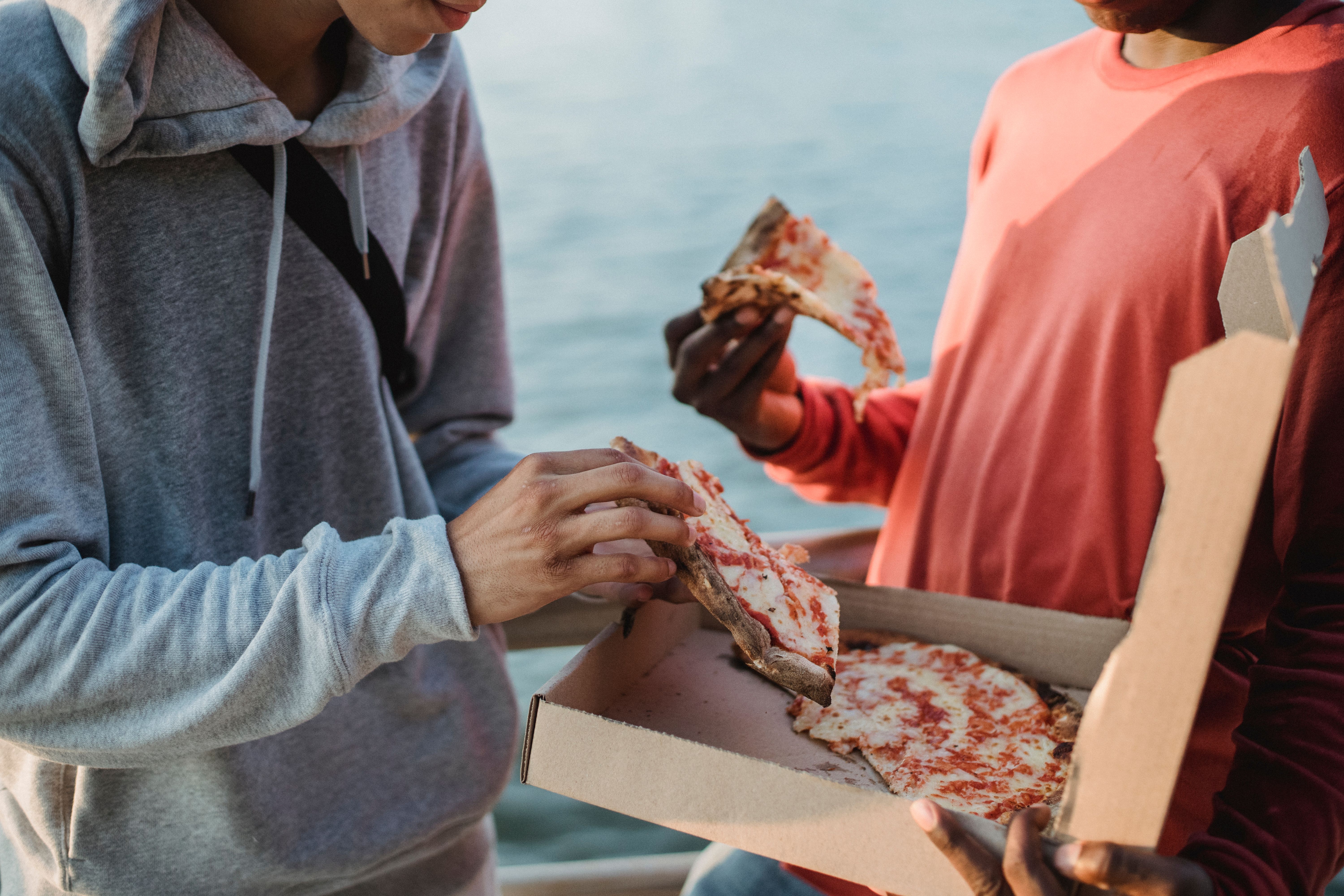 Two people eating pizza out of a box