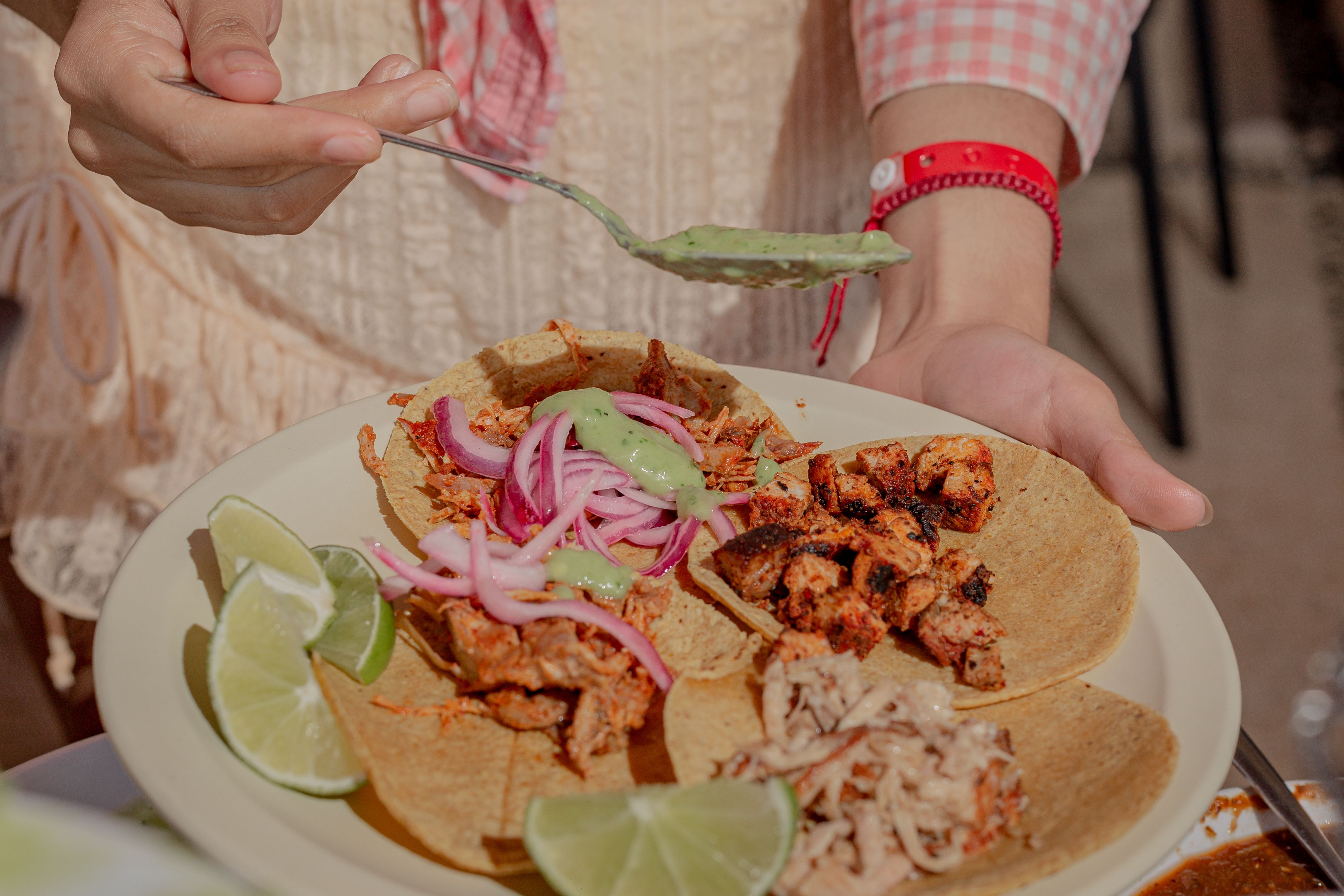 Person pouring sauce on tacos