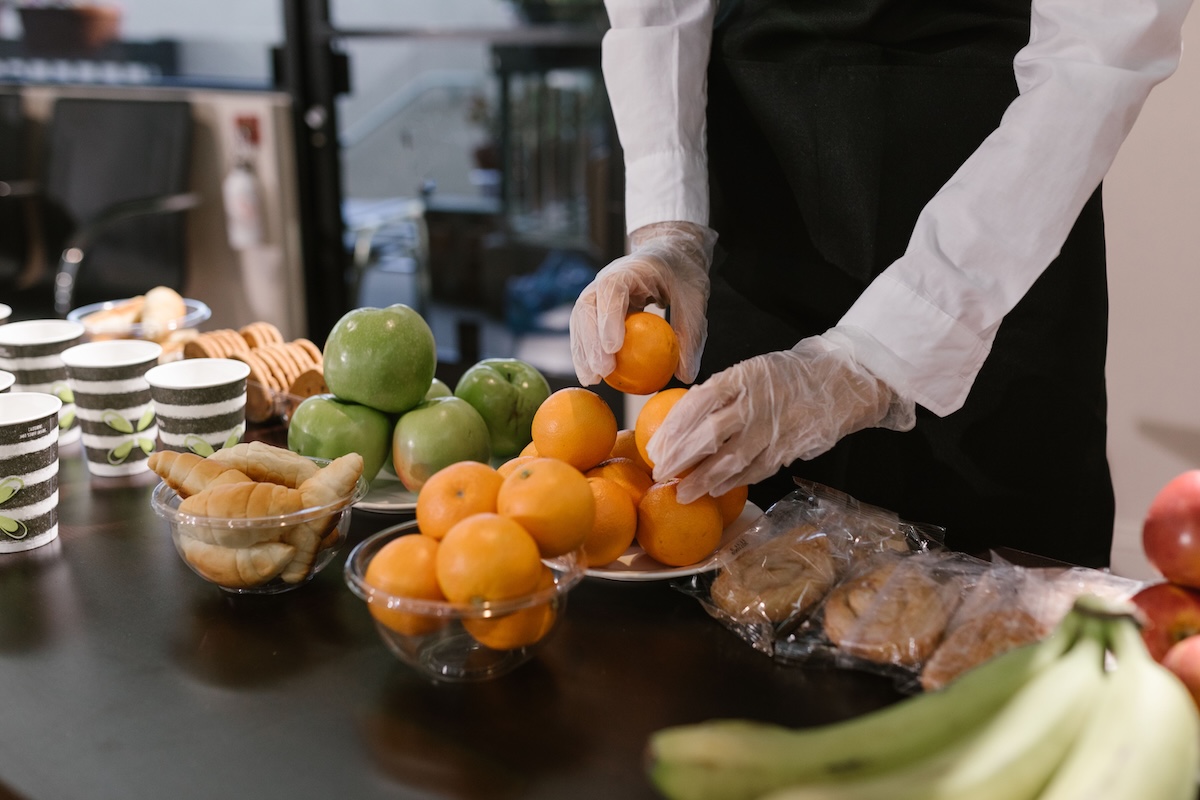 Waiter putting fruit in bowl while setting up catering station