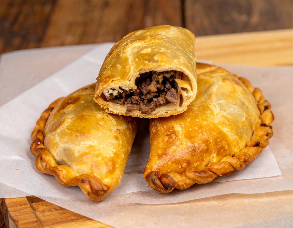 Trio of empanadas with one cut open to show filling