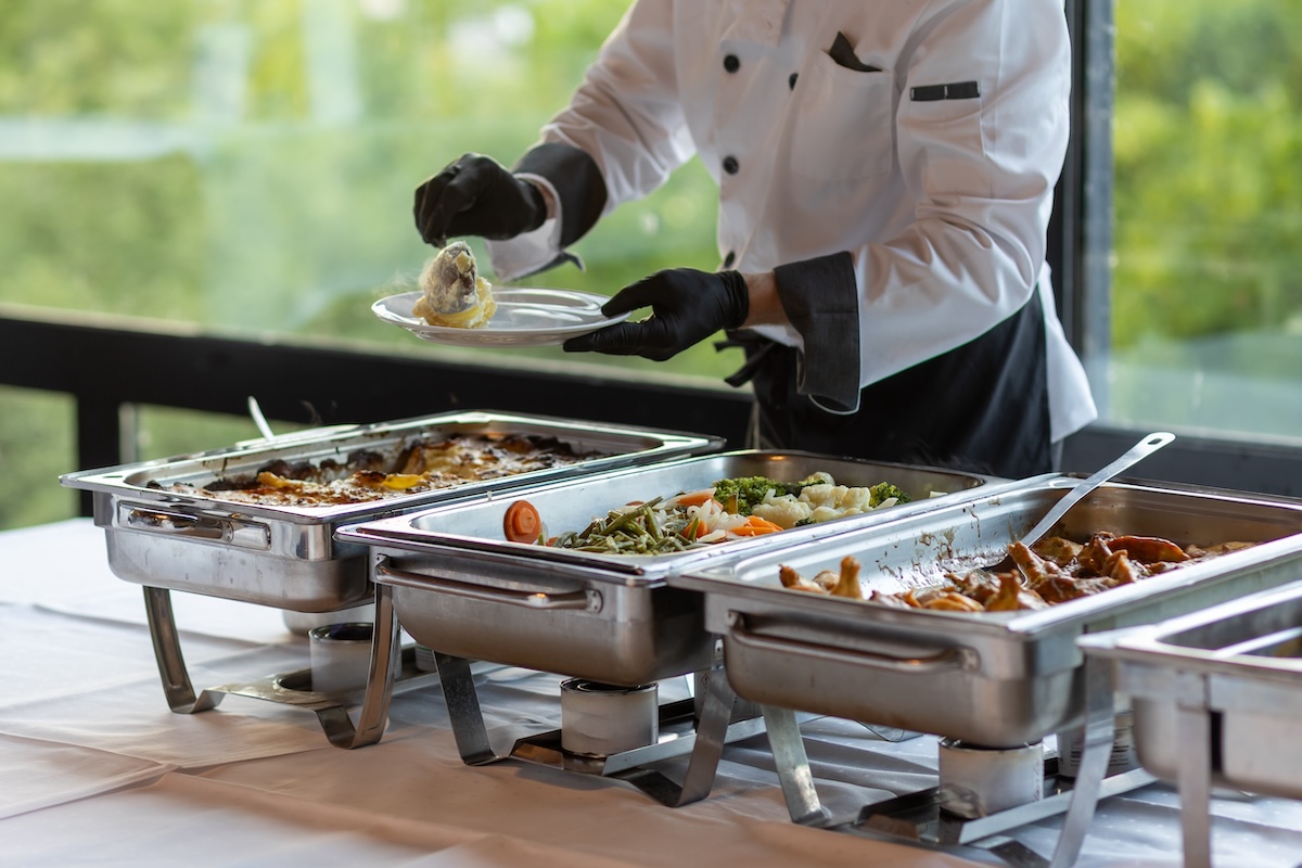 Catering server serving food onto plate