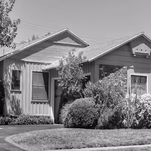 Grayscale image of a suburban home exterior with landscaping symbolizing pest-free living through pest control services.