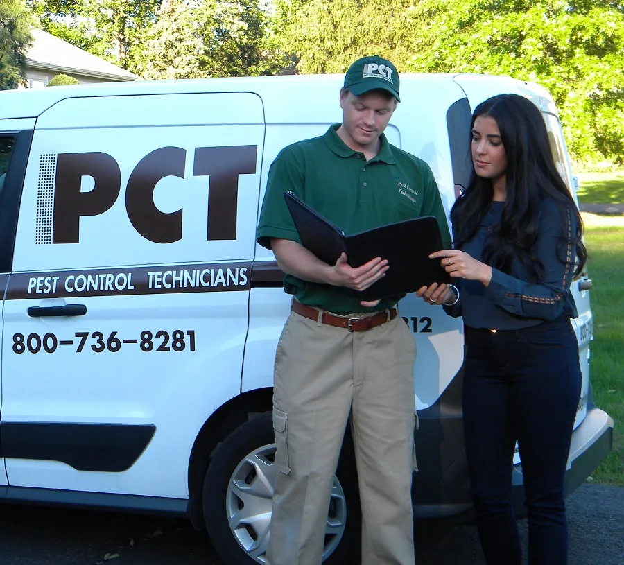 Pest control expert showing yard conditions to homeowner during tick pest control services.