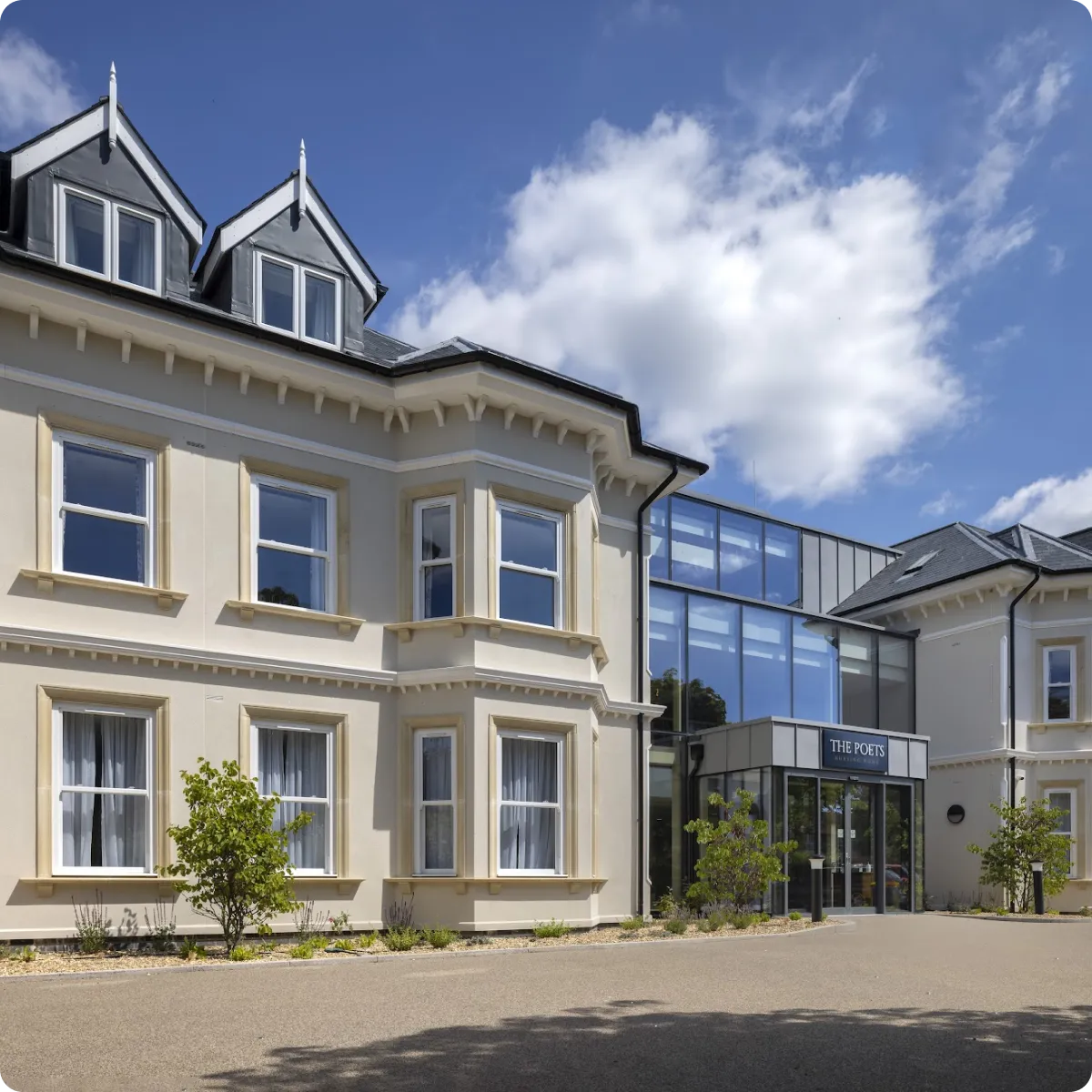 Exterior view of The Poets nursing home building with a modern glass entrance on a clear day.