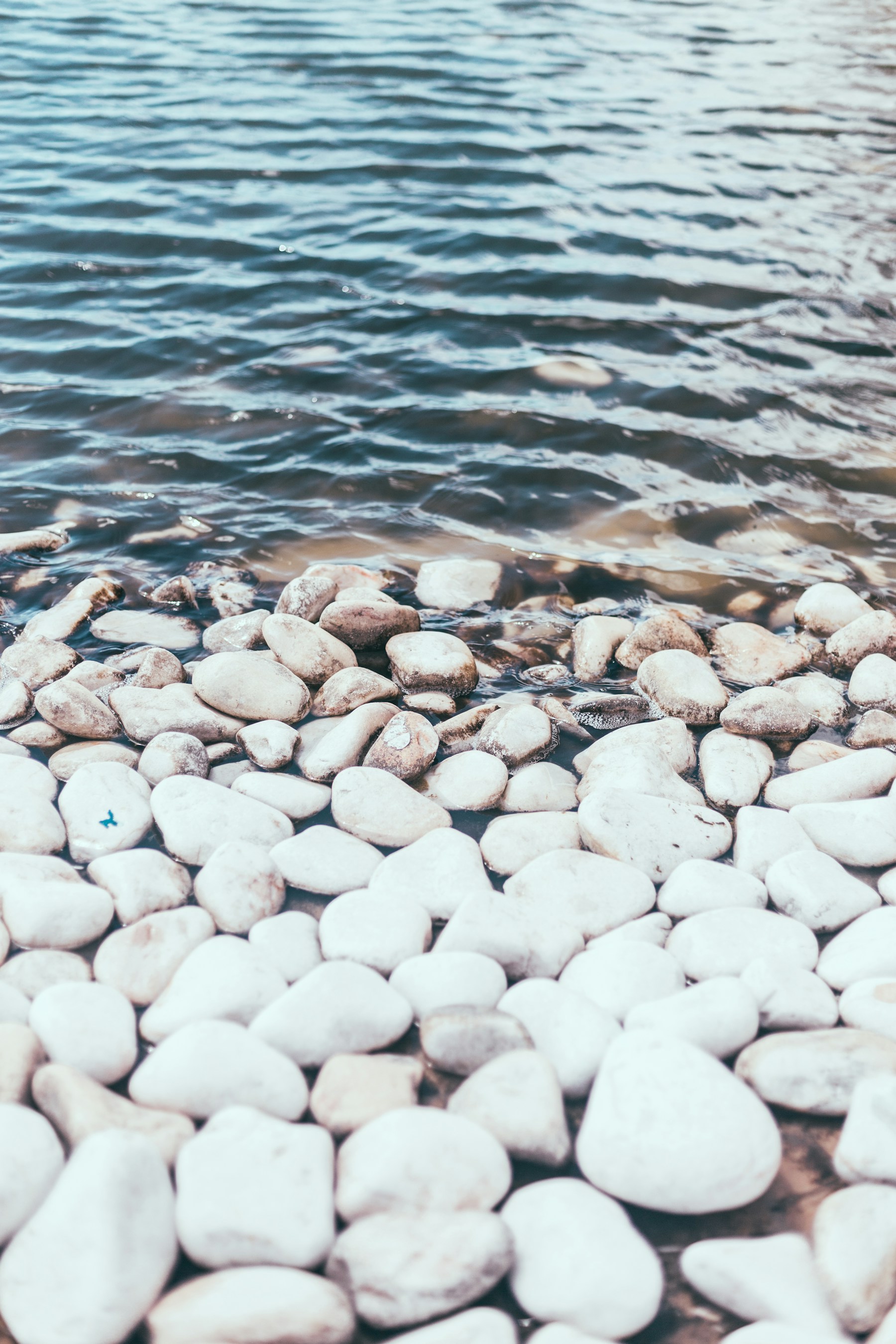 Smooth white and gray stones beneath gently rippling water