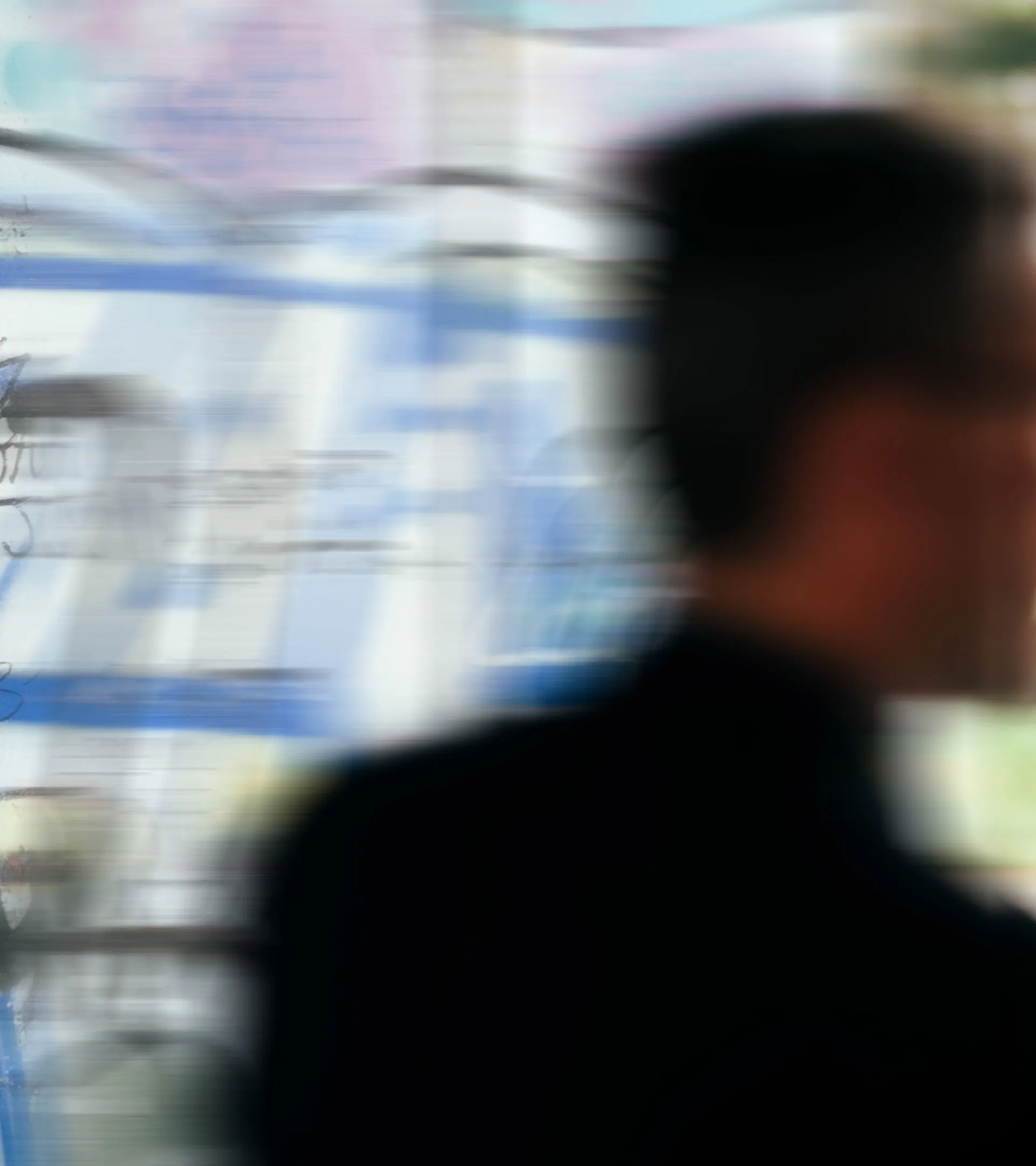 Unscharfes Profil eines Mannes vor einem Whiteboard mit skizzenhafter, blau und schwarz beschrifteter Darstellung.