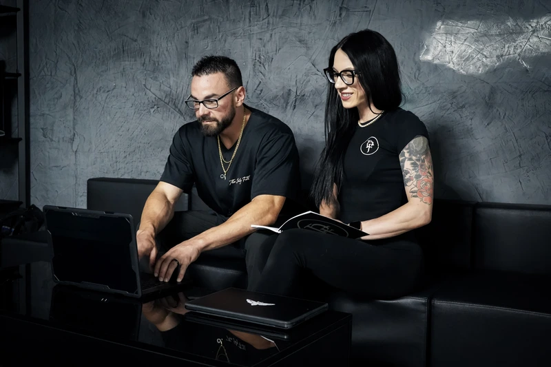 The Daily Fill Ali and JP sitting together on a couch, looking at a laptop