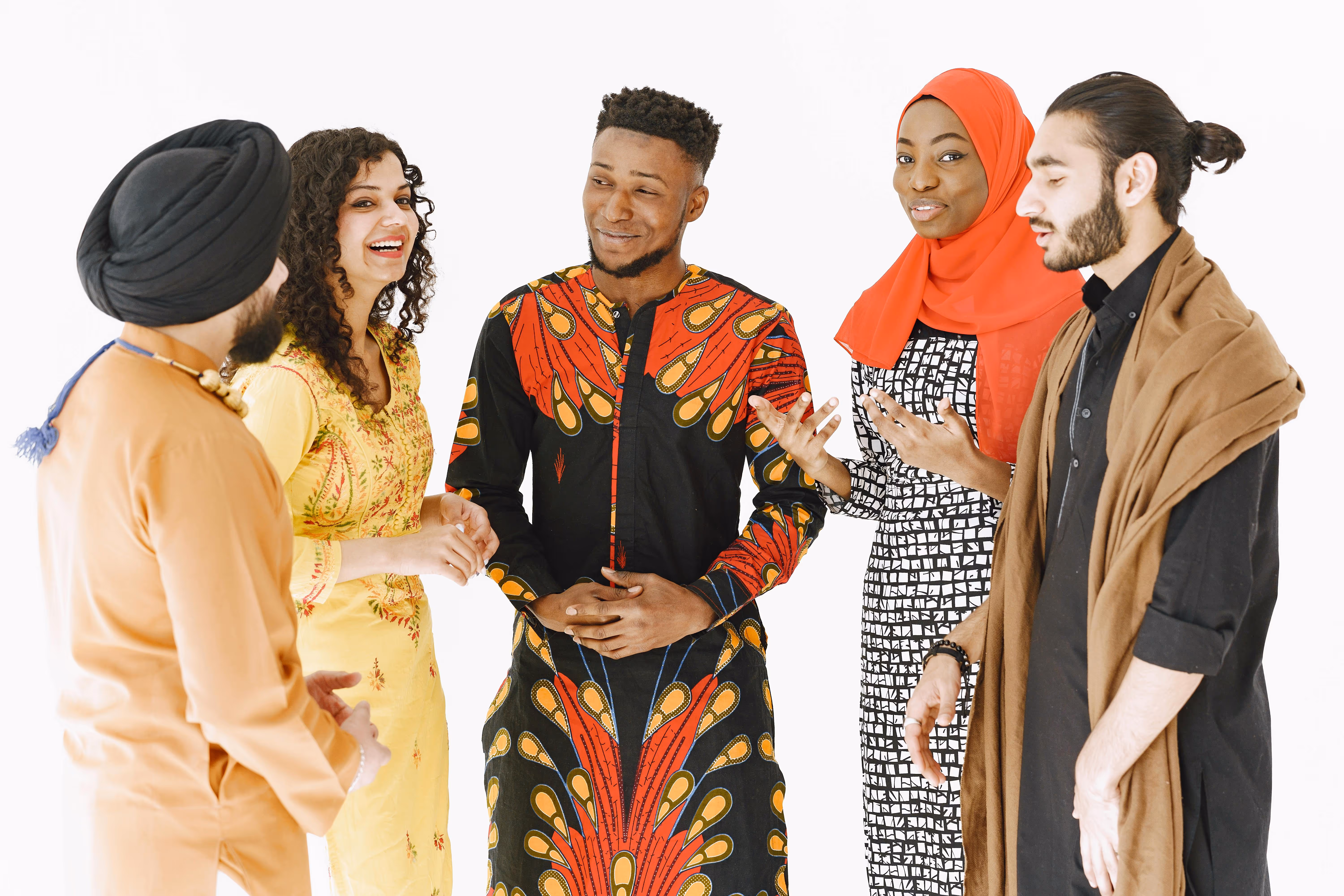 Group of five multicultural young adults smiling and talking, wearing diverse traditional and modern clothing.