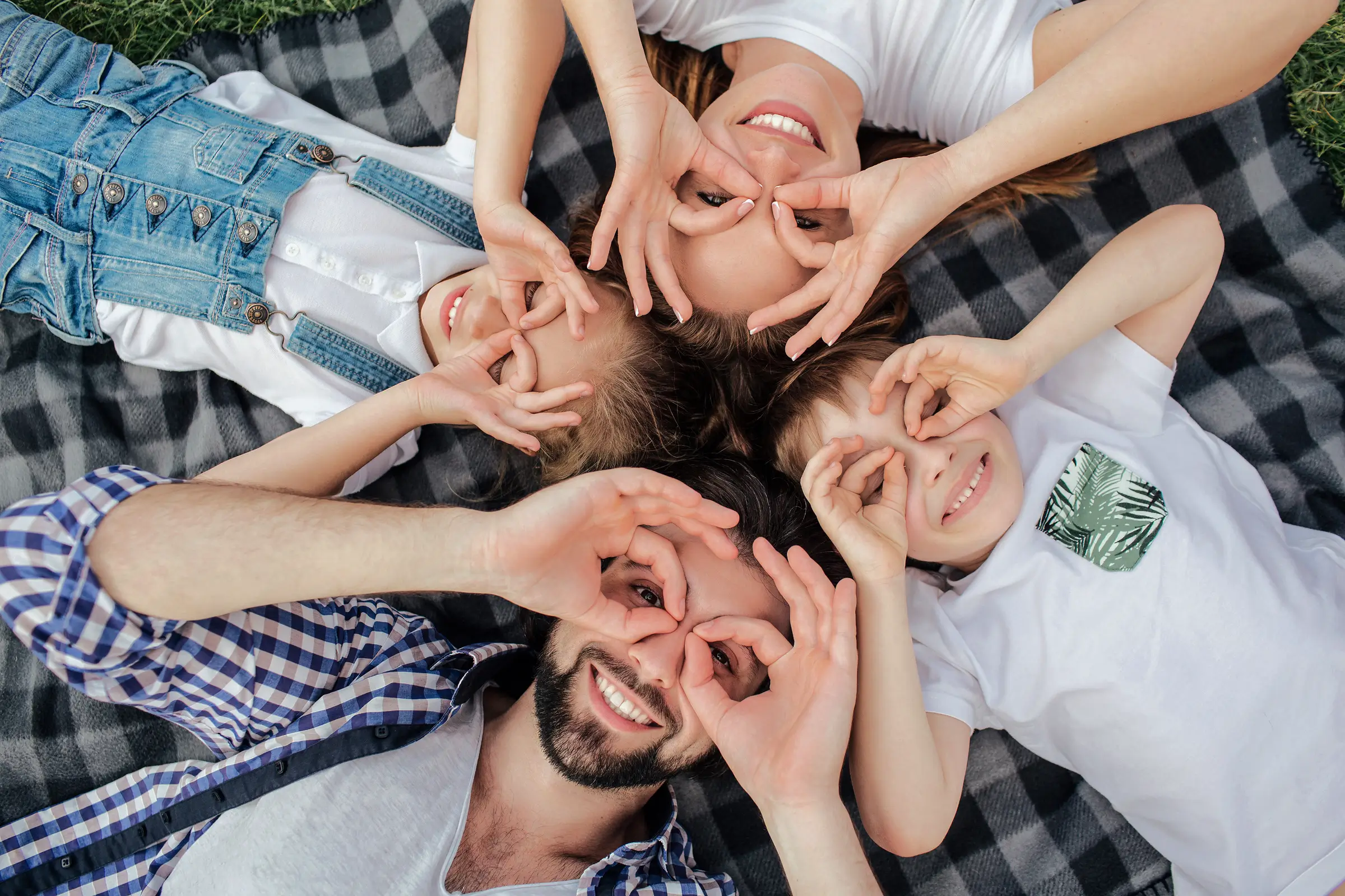 Family laying together making glasses over their eyes with their hands. 