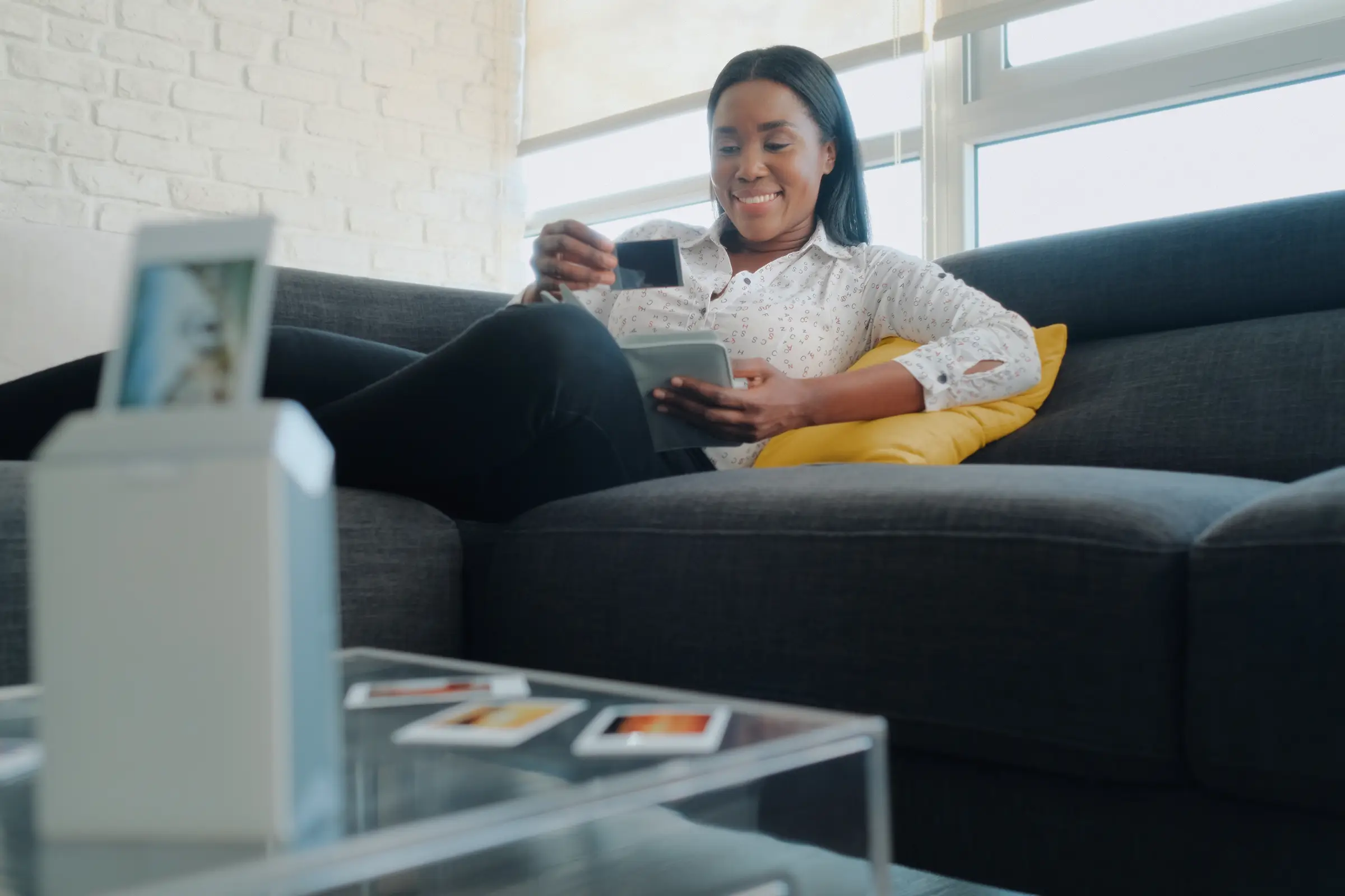 Woman looking at pictures in an album while relaxing on her couch.